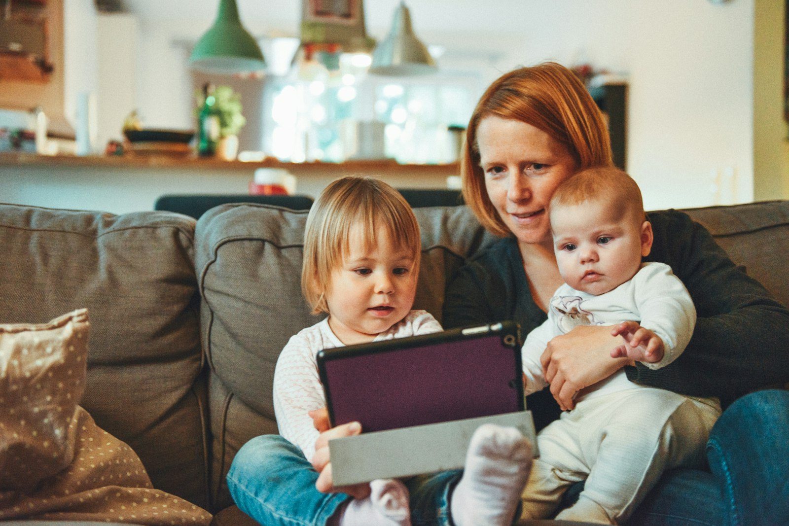 A parent and children on a sofa looking at a tablet together