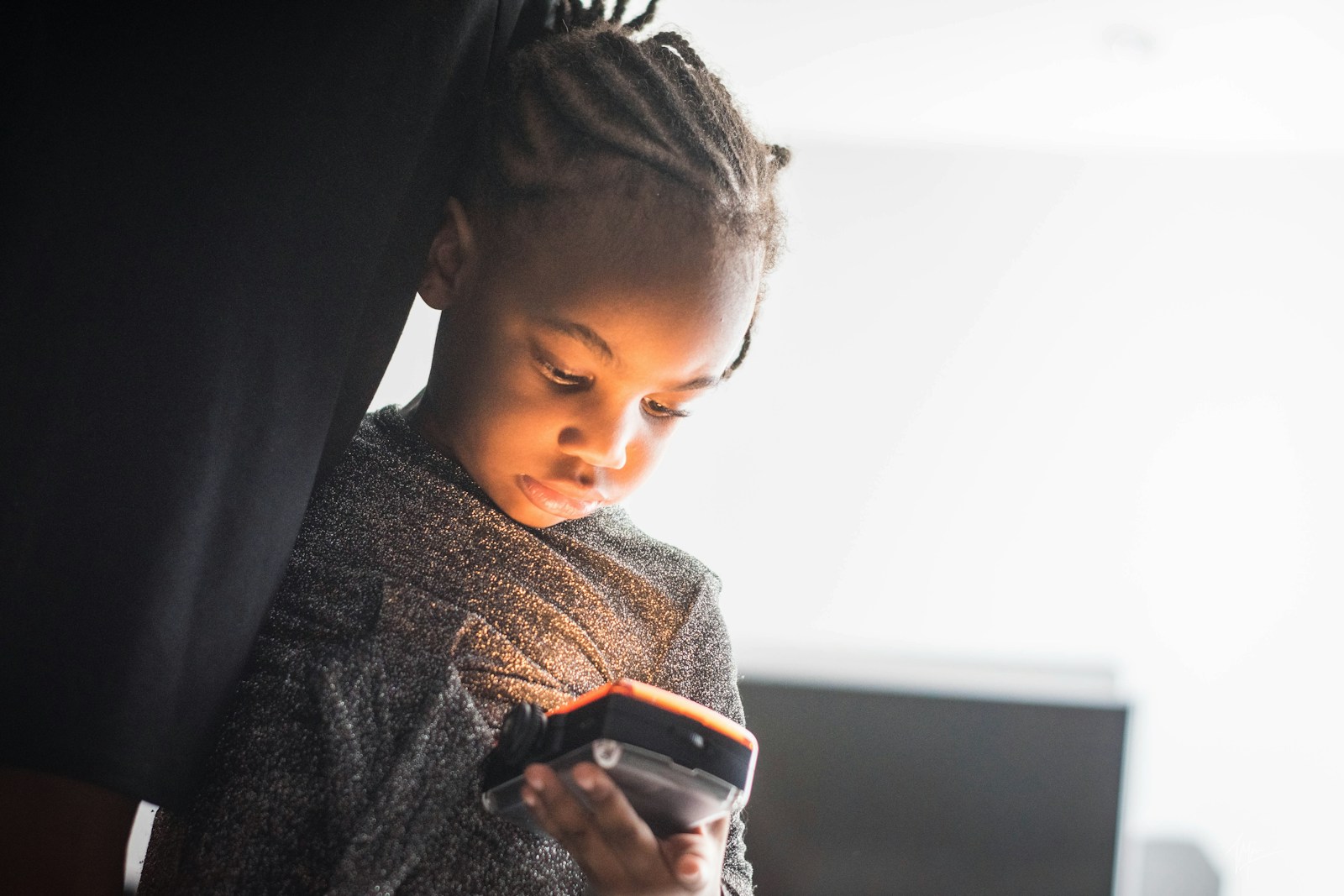 A boy holding a black smartphone, looking down at the screen