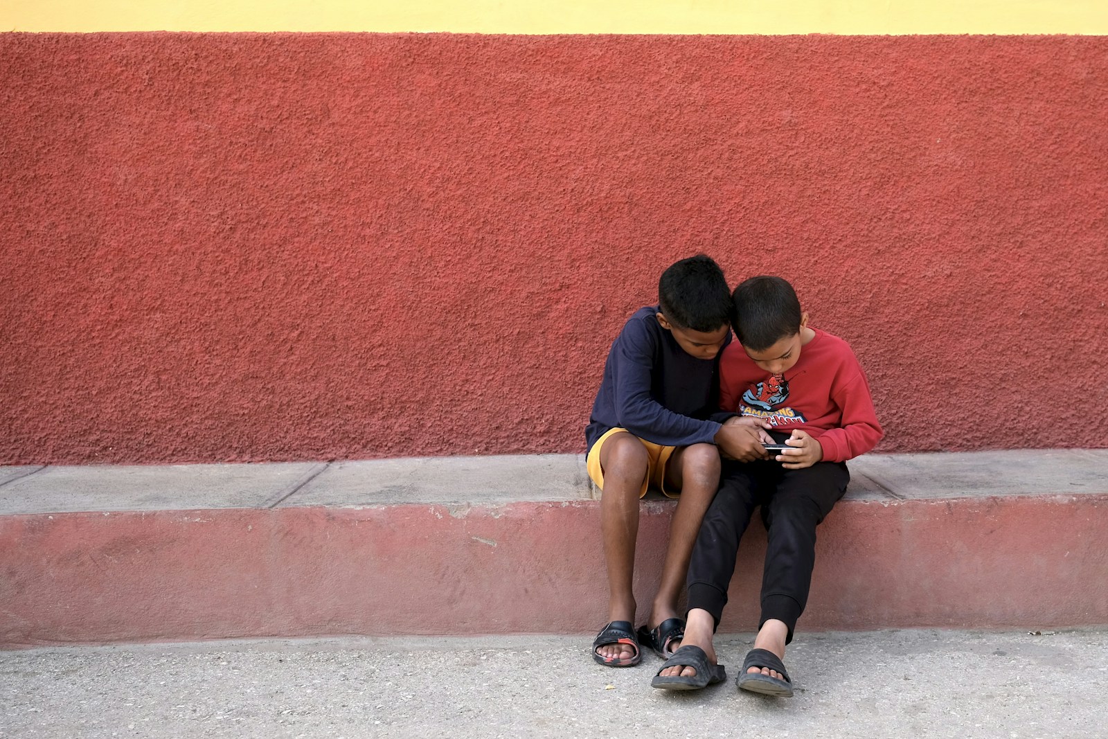 Two boys sitting together looking at a phone