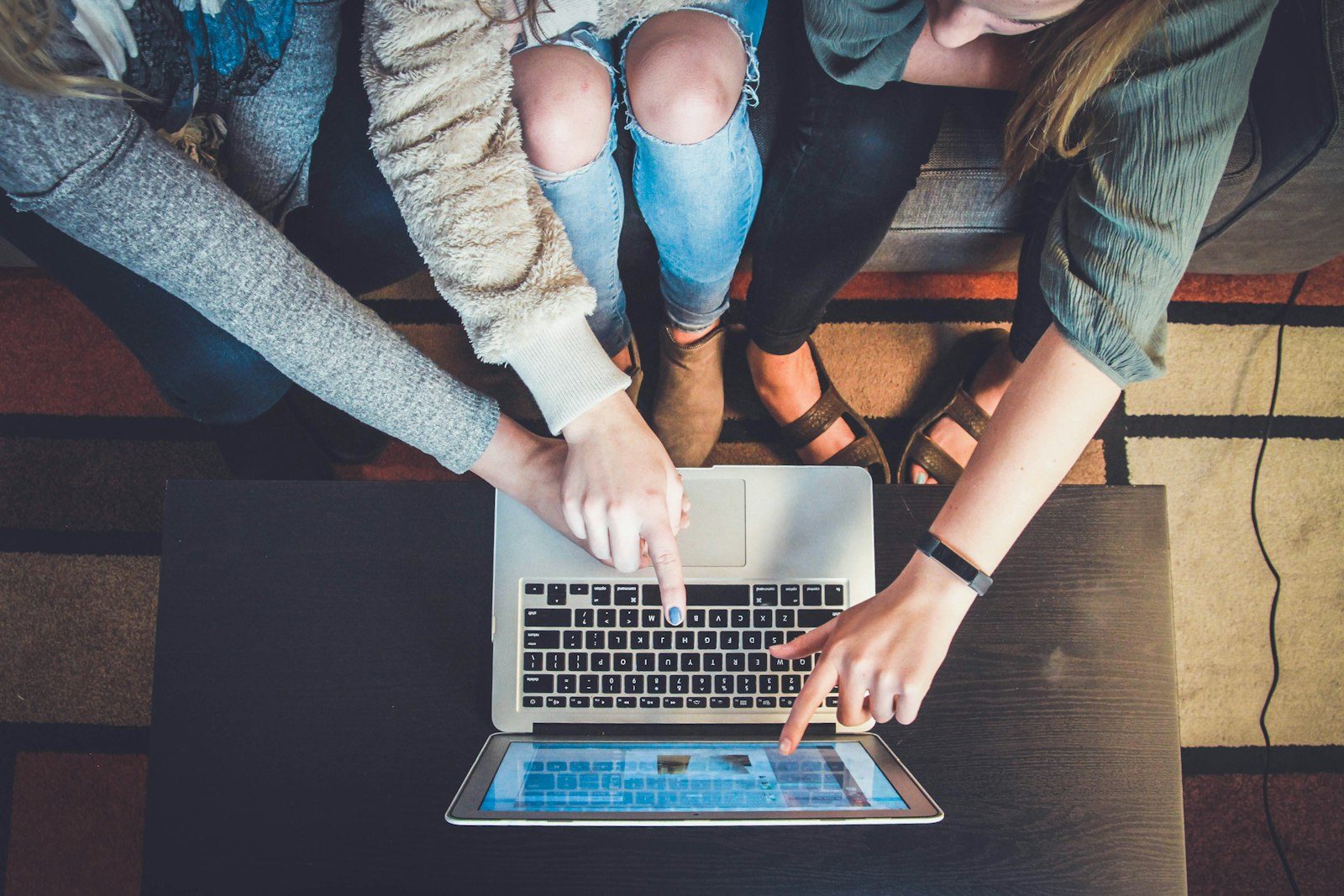 Three people gathered around a laptop, evaluating something together — the collaborative, question-asking habit at the core of digital literacy