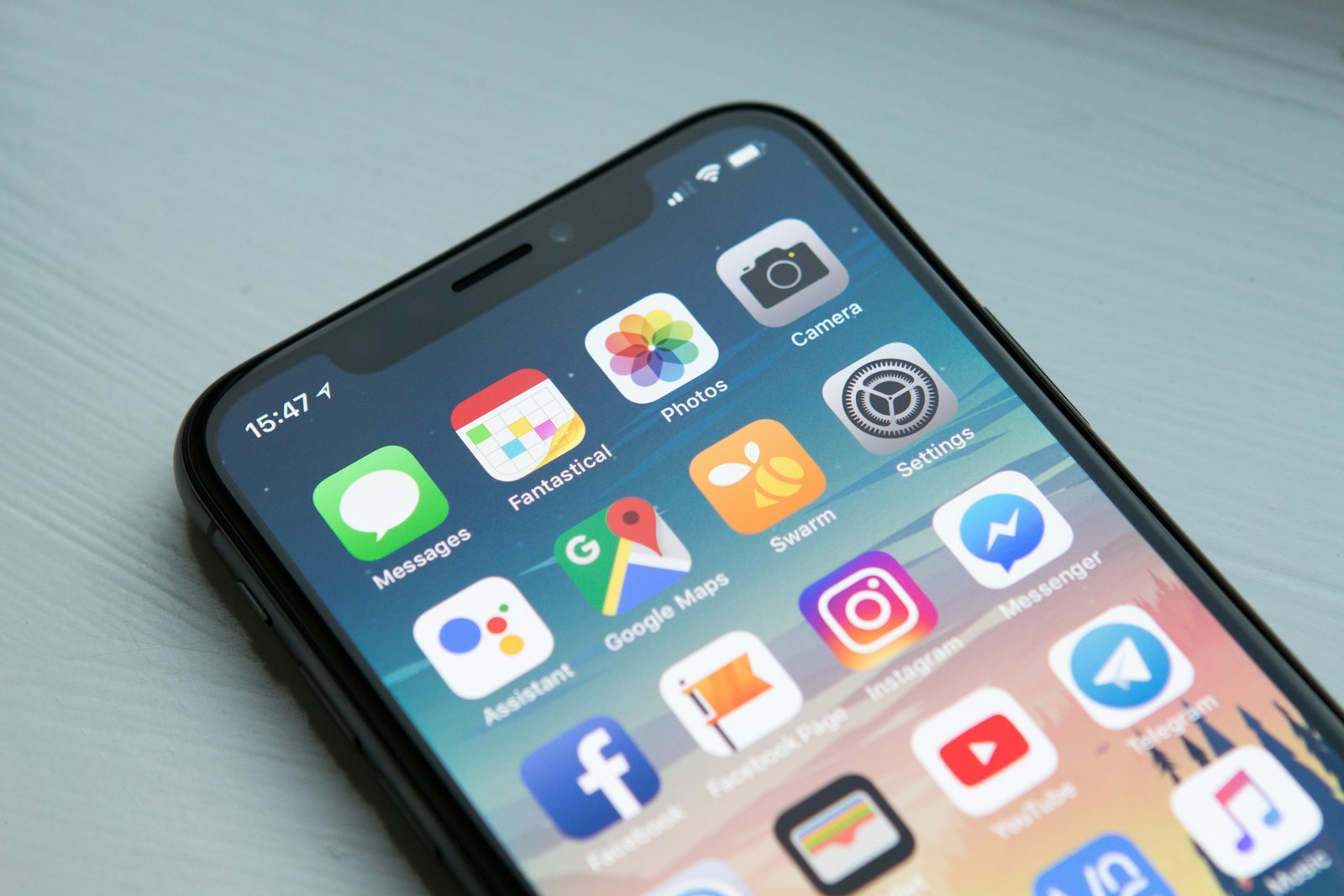 A smartphone lying on a table showing a home screen full of app icons