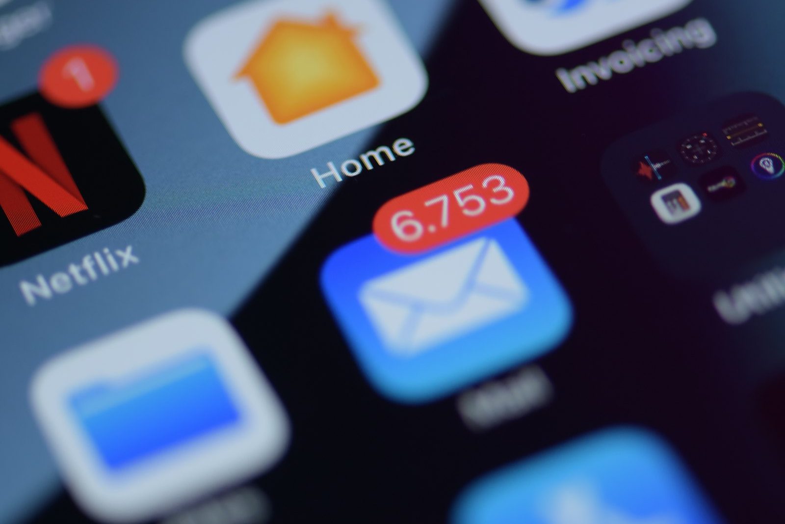 Close-up of a smartphone screen covered in app icons, several showing red notification badges