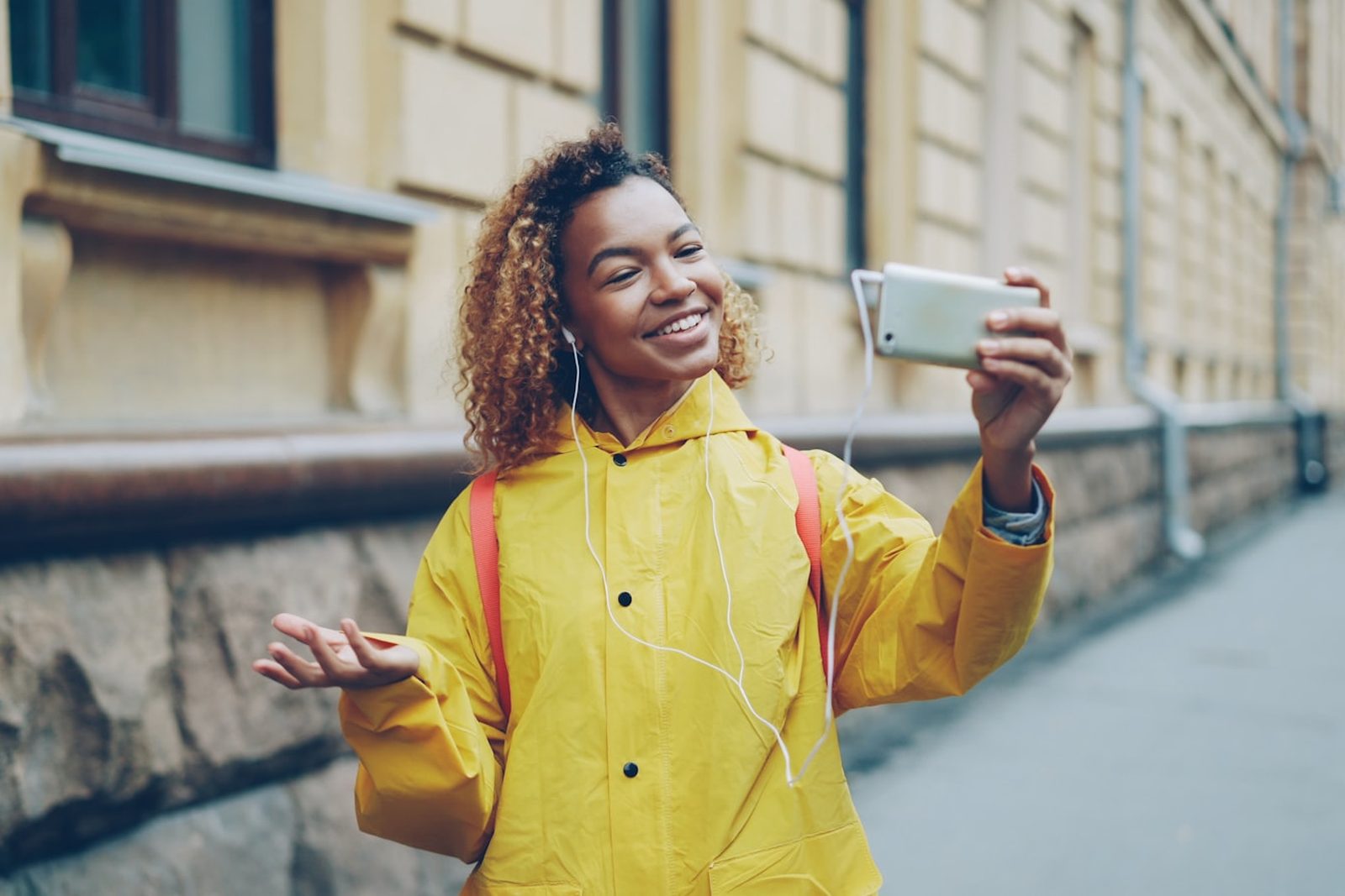 A young woman taking a selfie on a city street — the ordinary moment where oversharing actually happens