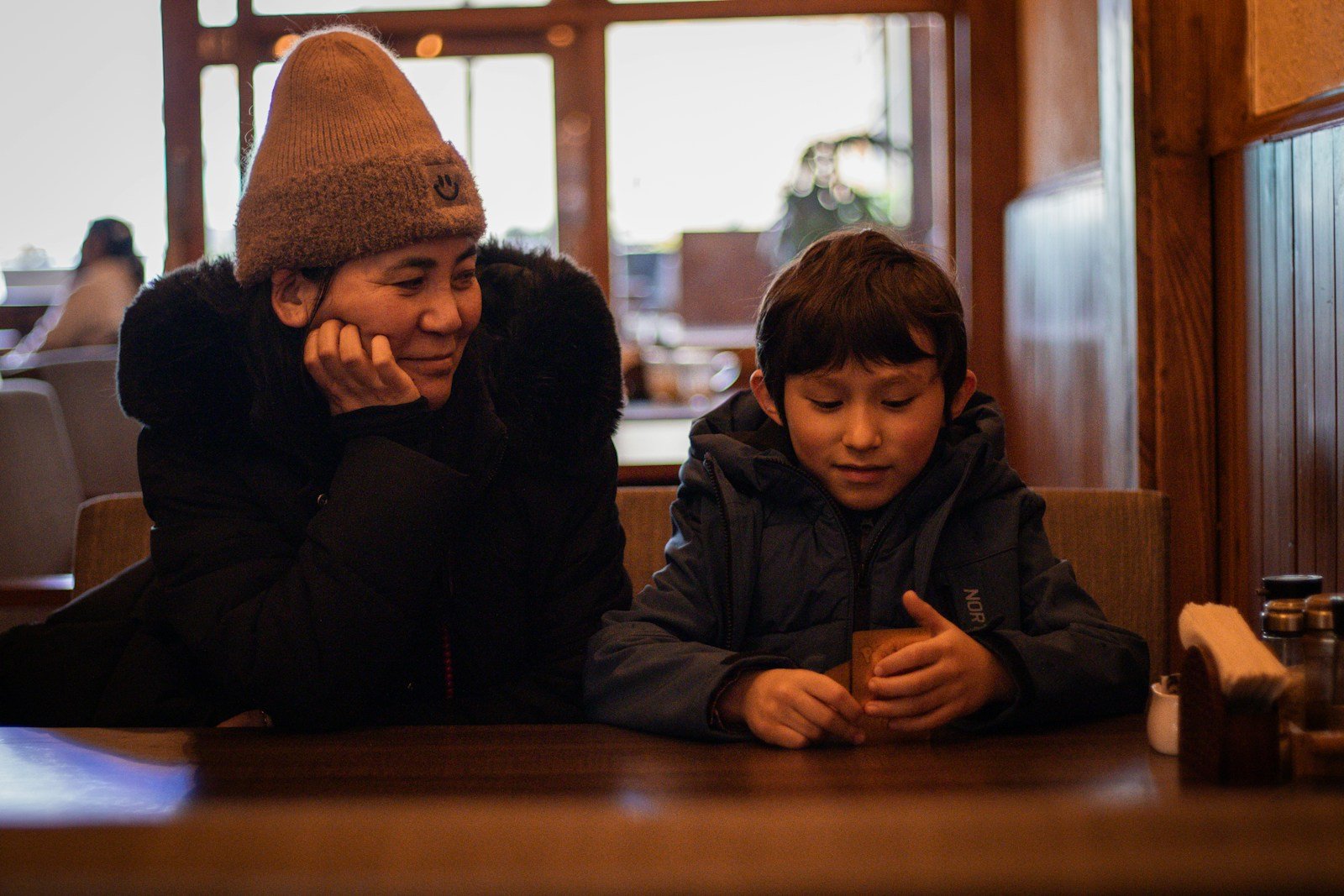 A parent and child sitting together at a table, engaged in conversation